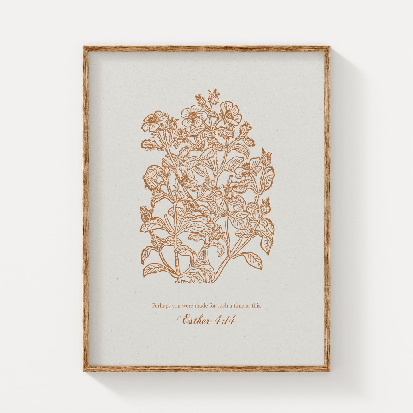 Close-up of the botanical art print featuring golden floral illustrations and Esther 4:14, framed in natural wood on a plain white background.