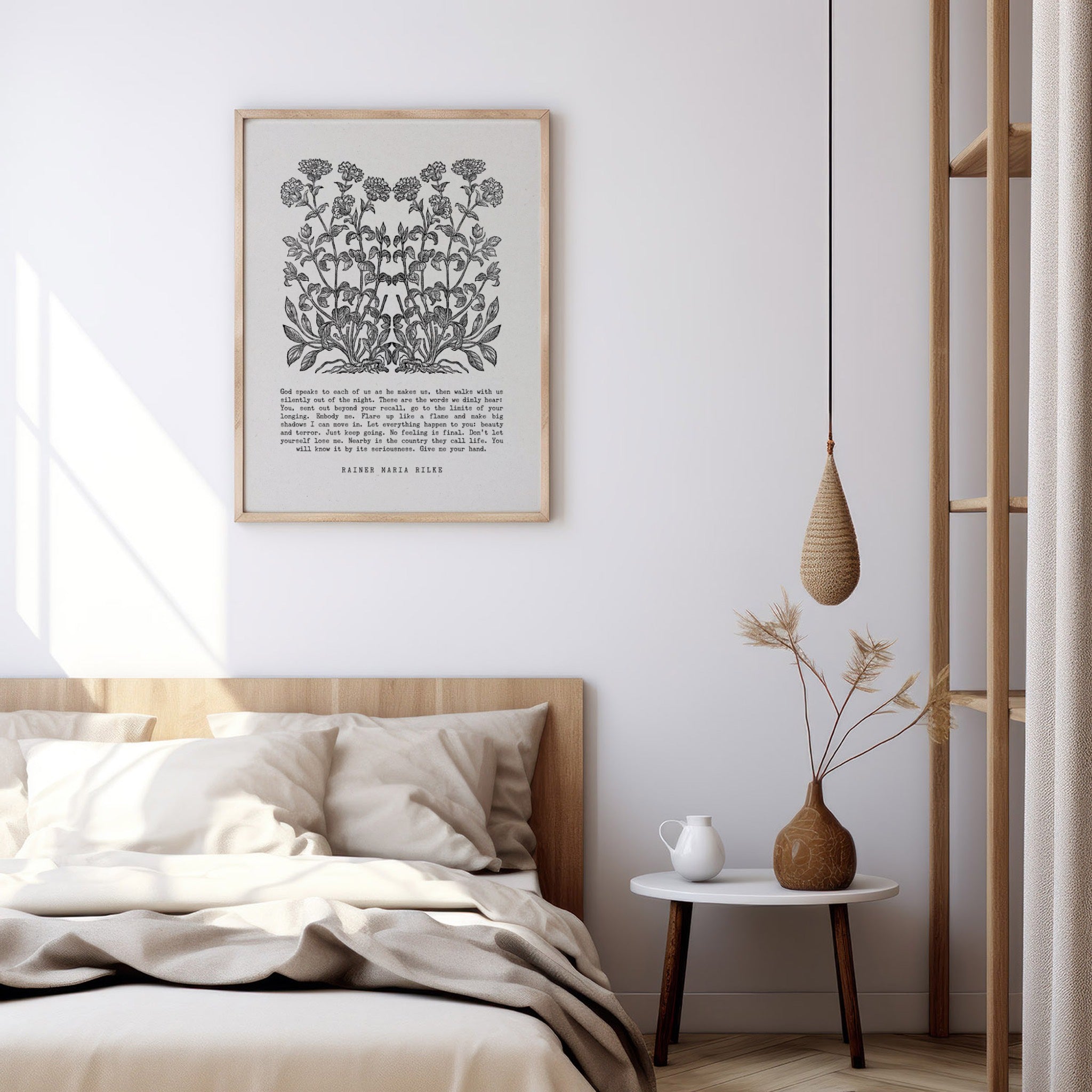 Art print with black floral designs and Rainer Maria Rilke’s text styled above a neutral bed with soft bedding and a minimalist bedside table featuring a modern vase and candle.
