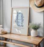 Botanical art print featuring blue floral designs and Joshua 1:9, leaning on a wooden bench with decor including a white vase of greenery and vintage teacups.