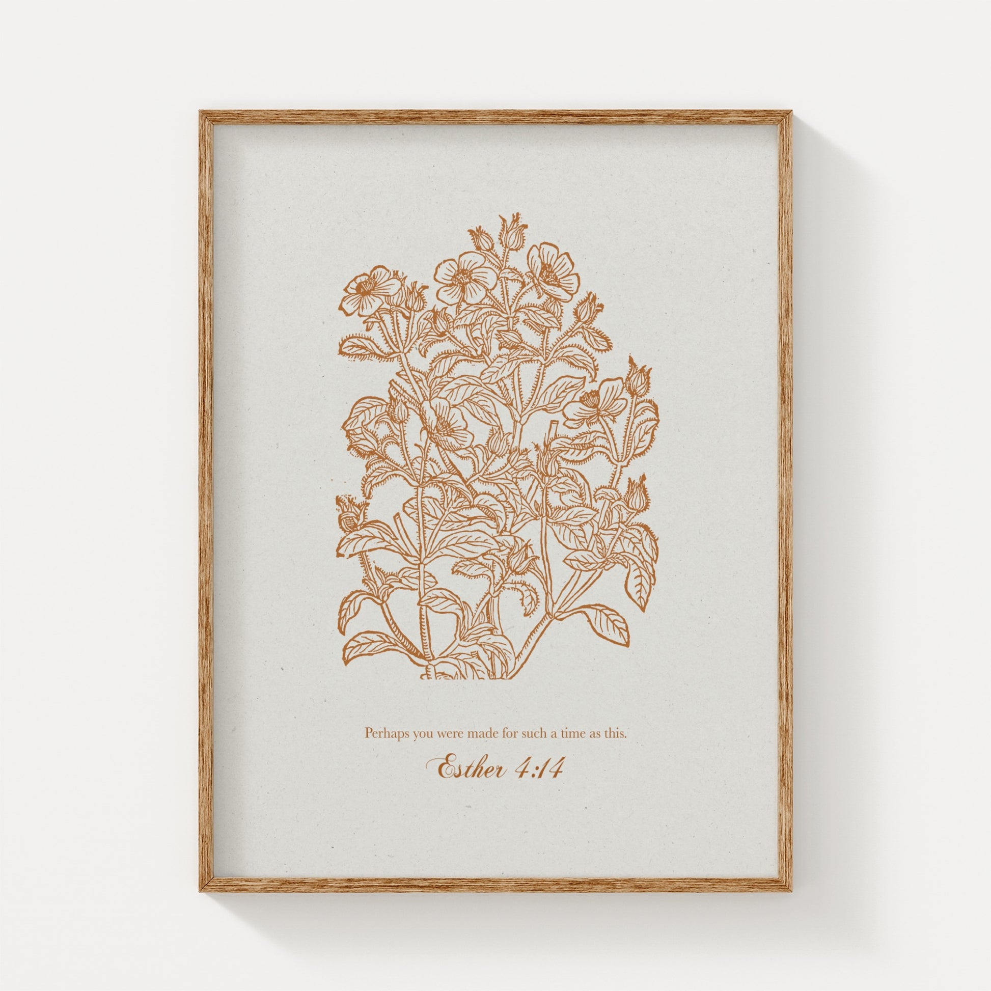 Close-up of the botanical art print featuring golden floral illustrations and Esther 4:14, framed in natural wood on a plain white background.