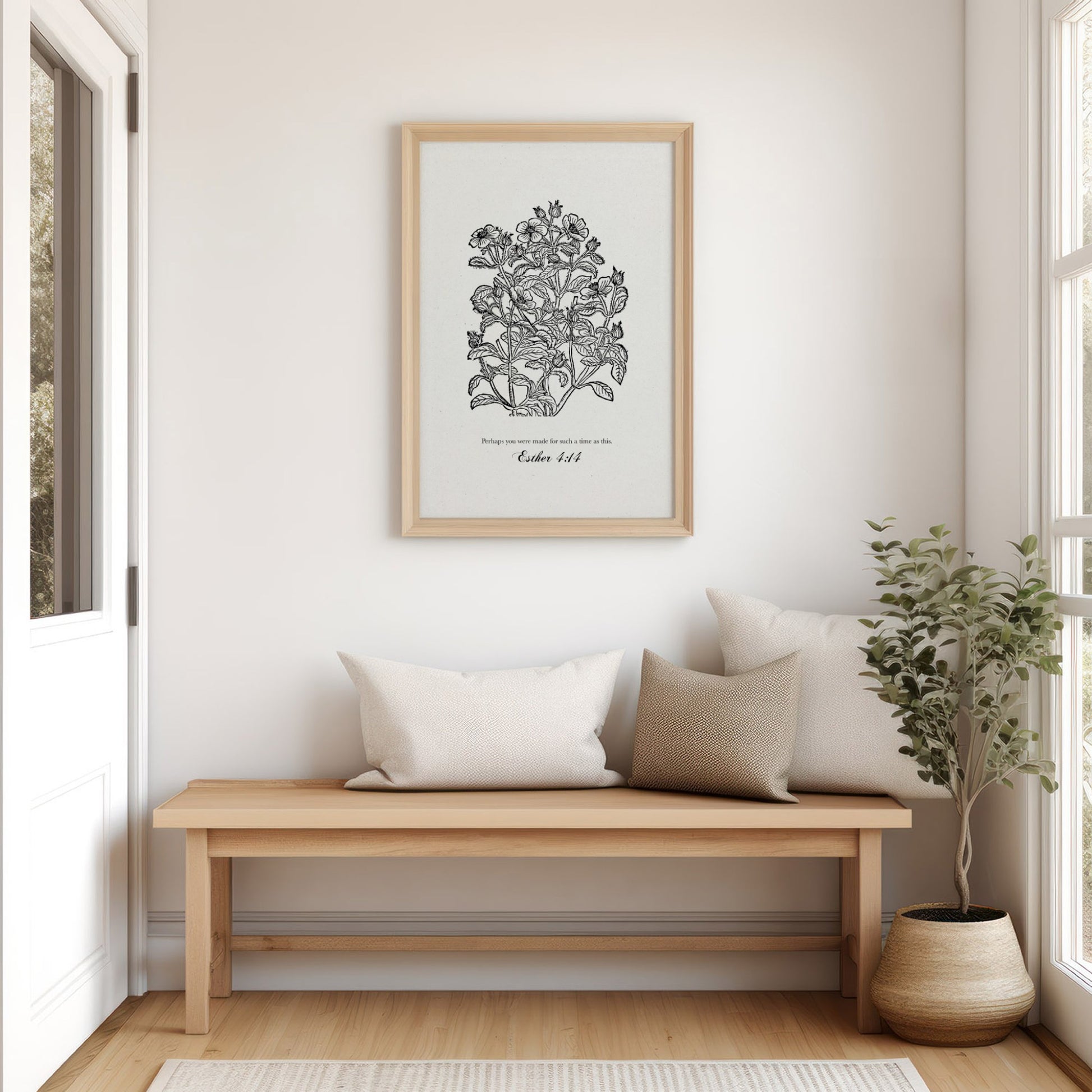 Art print with black floral designs and Esther 4:14 styled in a serene living space above a wooden bench, with soft pillows and a potted plant.