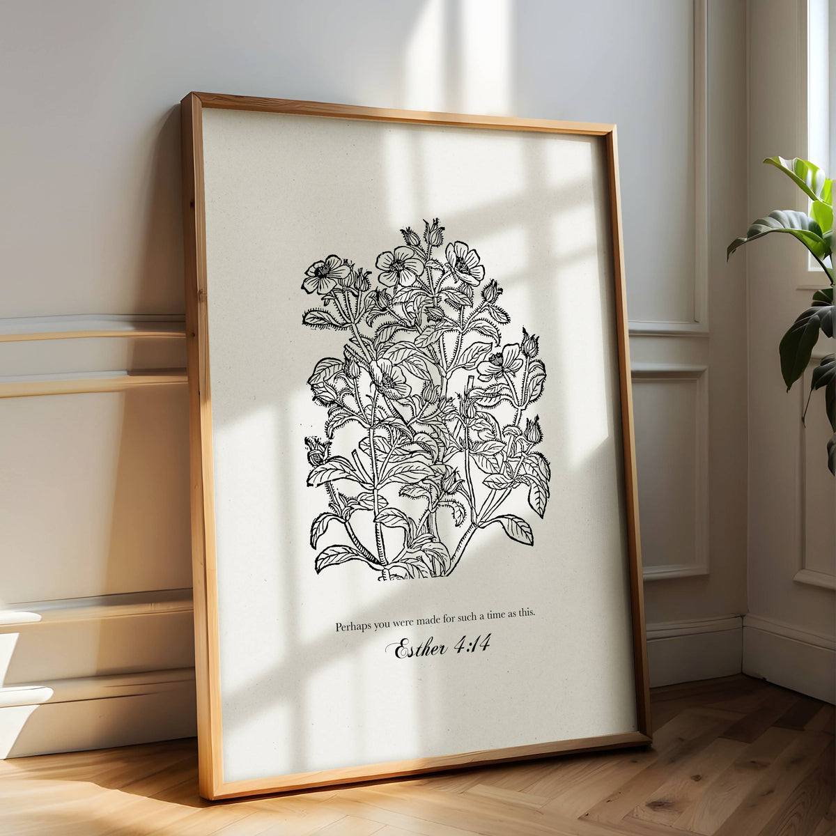 Framed Christian botanical print with a quote on a white wall.