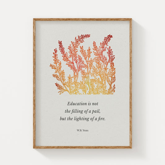A framed art print featuring W.B. Yeats’ quote about education, elegantly paired with warm-toned botanical illustrations in shades of red and gold, displayed on a neutral background with a natural wood frame.
