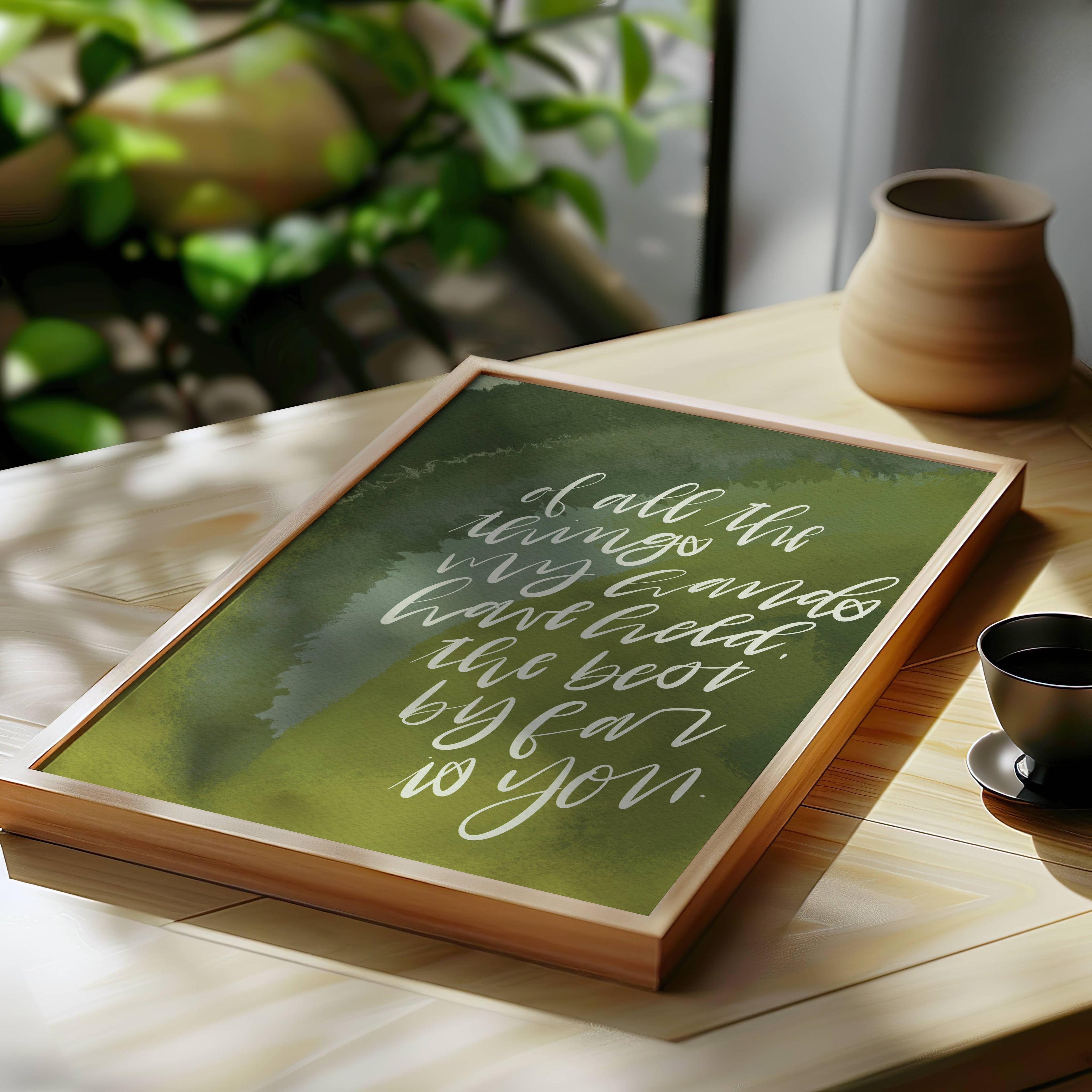 Framed quote on a table with a cup and plant in the background