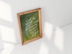 Framed handlettered artwork with text on a white wall