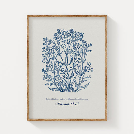 Botanical art print featuring delicate blue floral illustrations paired with the Bible verse Romans 12:12, displayed in a natural wood frame on a light background.