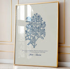 Close-up of a botanical art print with intricate blue floral details and a Jane Austen quote, elegantly framed in gold and styled against a paneled wall with natural light streaming in.