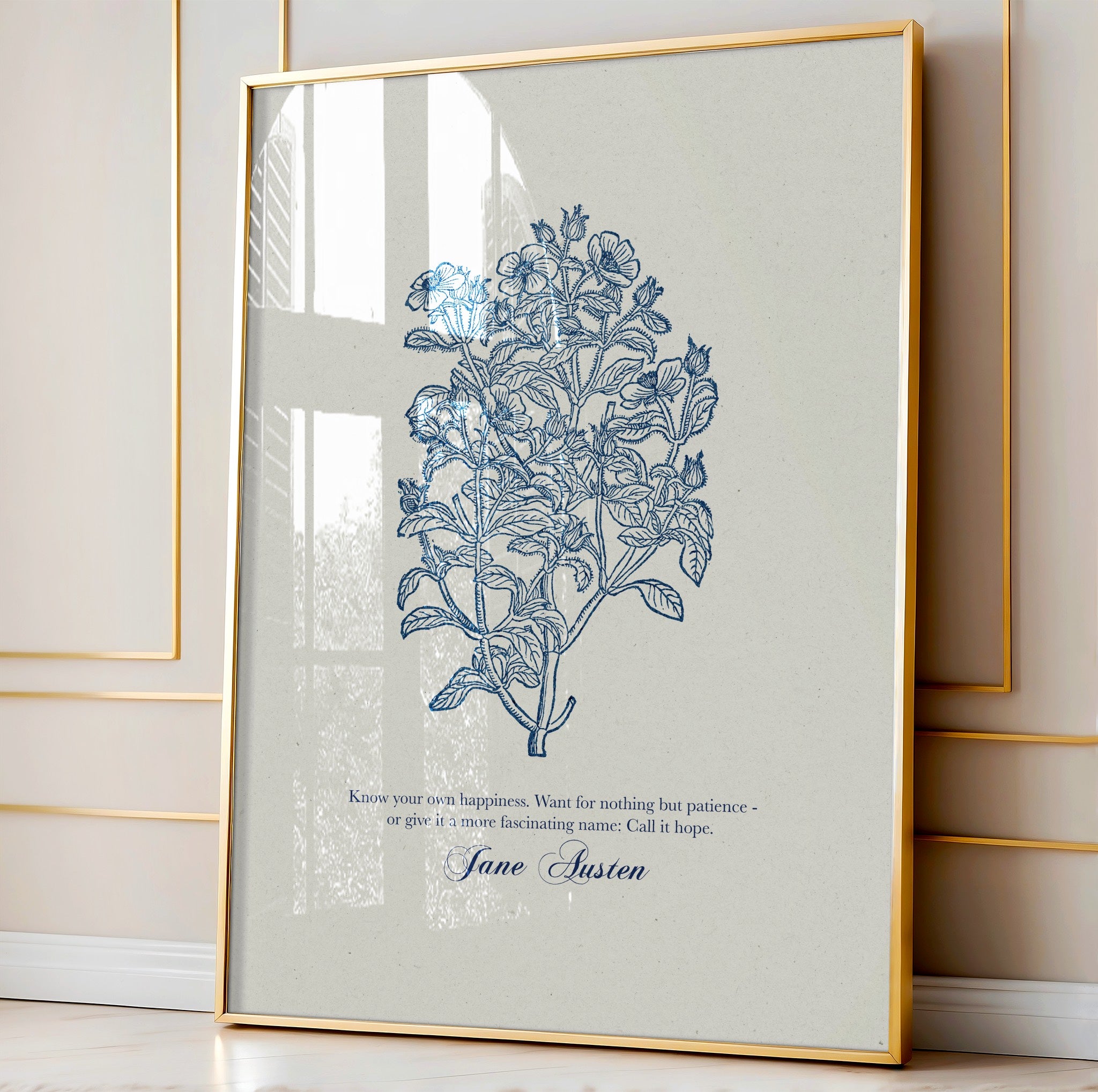 Close-up of a botanical art print with intricate blue floral details and a Jane Austen quote, elegantly framed in gold and styled against a paneled wall with natural light streaming in.