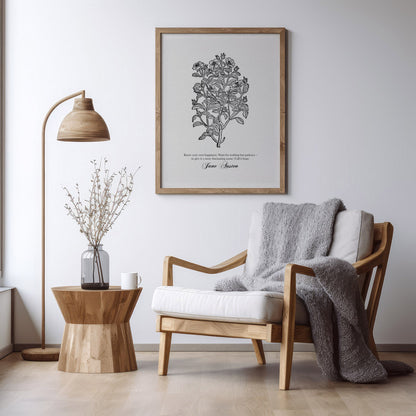 Black floral botanical art print featuring a Jane Austen quote, framed in natural wood and styled in a serene living room setting with a modern wooden chair, a side table, and a soft gray throw blanket.