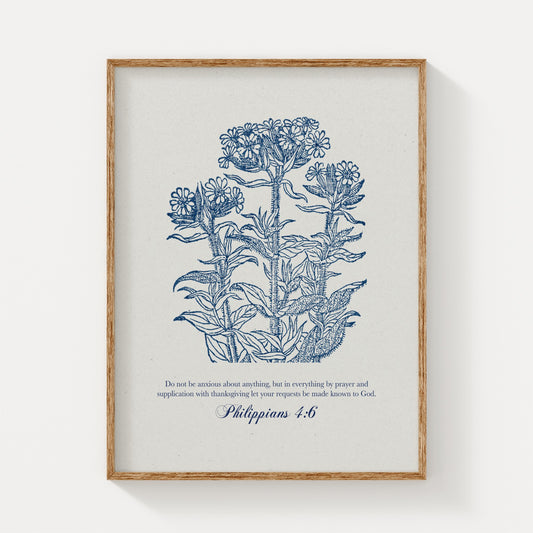 Botanical art print featuring intricate blue floral illustrations and the Bible verse Philippians 4:6, displayed in a natural wood frame on a plain light background.