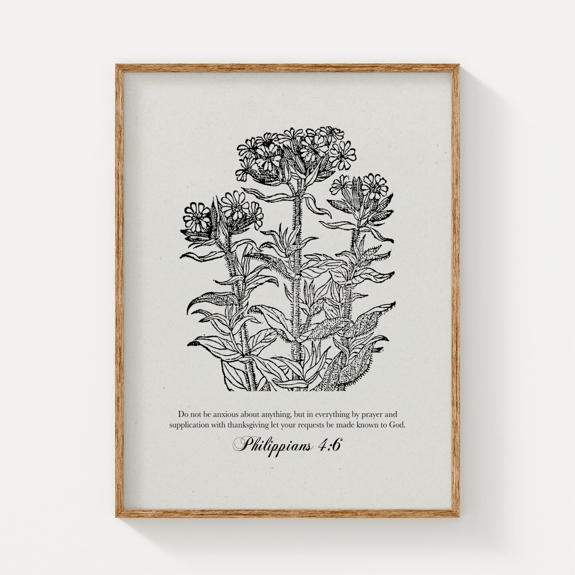 Black vintage floral botanical print featuring Philippians 4:6, displayed in a natural wood frame on a clean, white background for a minimalist look.