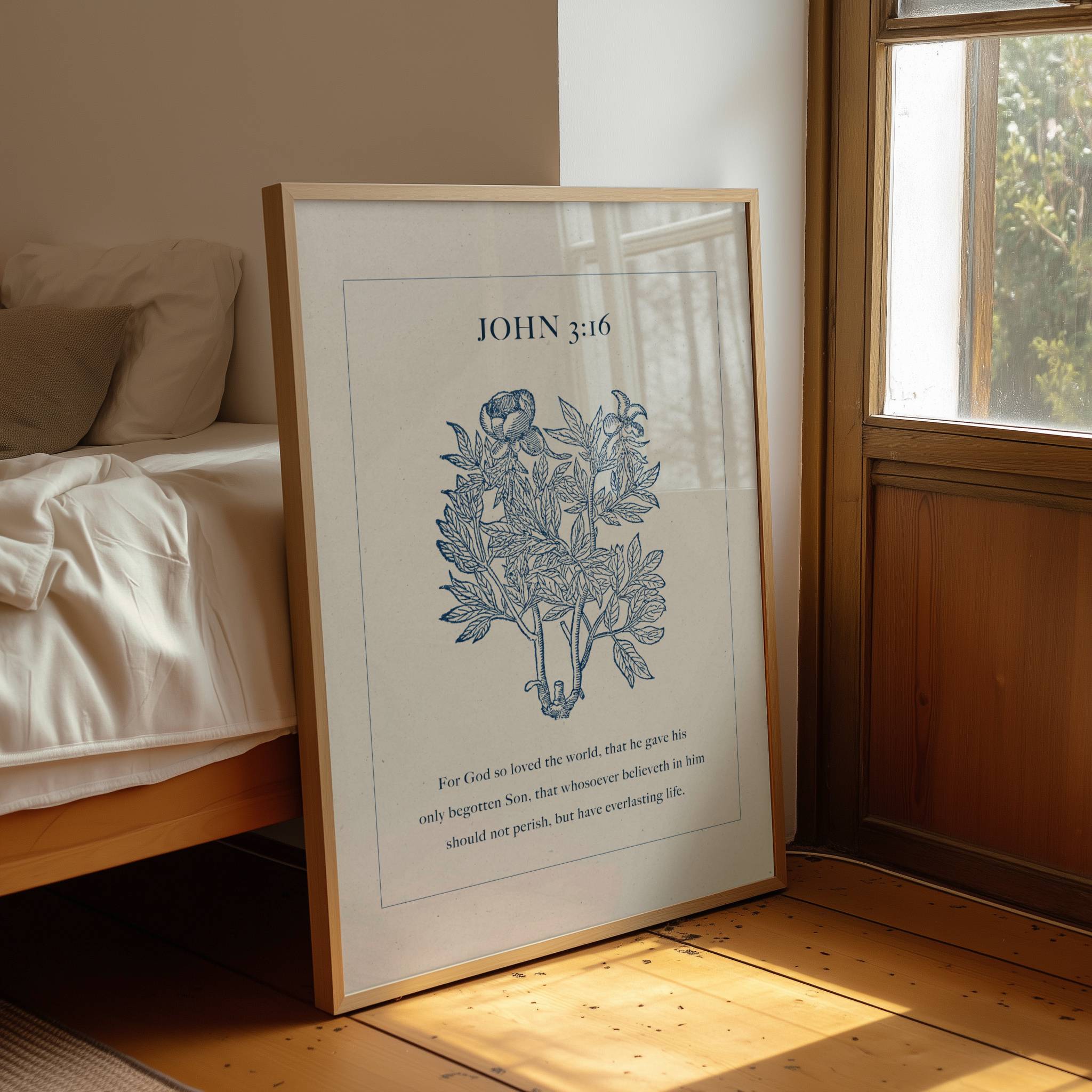 Framed artwork with 'John 3:16' text and plant illustration on a wooden floor.