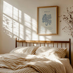 Bedroom with wooden headboard, striped bedding, and framed artwork featuring John 3:16 Scripture and blue botanical on wall.