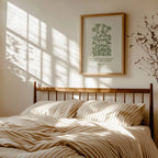 Bedroom with wooden headboard, striped bedding, and framed botanical art featuring John Muir Forest Wilderness quote by Reflourish Collective on wall.