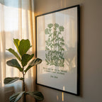 Framed botanical print featuring John Muir Forest Wilderness quote and beautiful floral art on a wall with a plant next to it