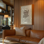 Brown leather sofa with a white pillow in a room with wooden walls and a framed botanical print.