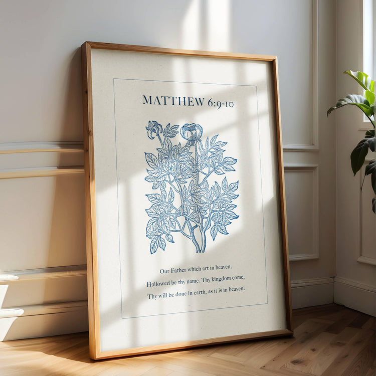 Framed botanical print with Bible verse from Matthew 6:9-10 on a wall in a room with a plant.